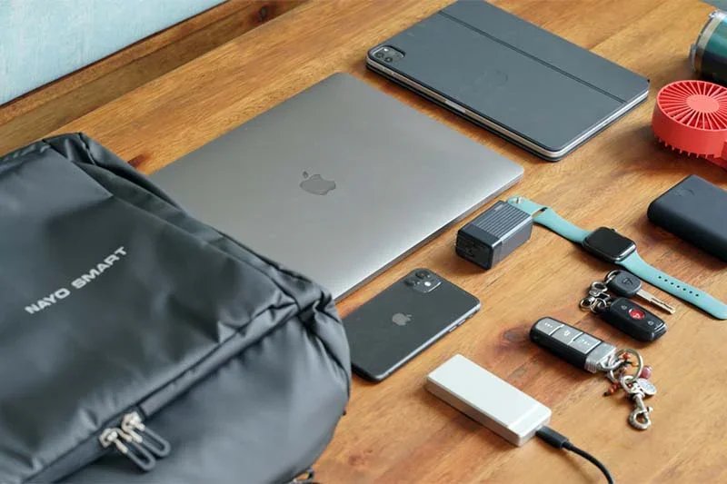 A compact travel work setup with a backpack, laptop and charging accessories