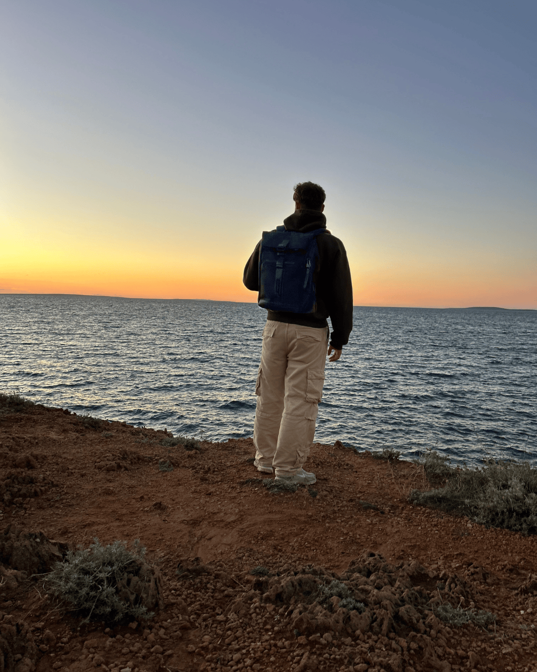 Johannes with his backpack on a coastal trip at sunset